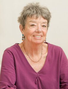 Smiling elderly woman in a purple top.
