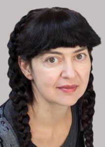Portrait of a woman with braided black hair and a calm expression.