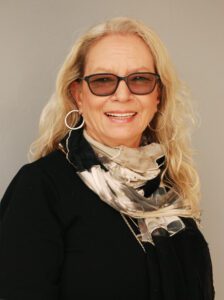 Smiling woman with glasses and a patterned scarf.