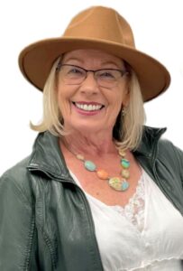 Smiling woman wearing a hat and glasses.
