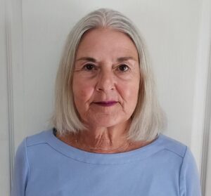 Portrait of an elderly woman with gray hair in a light blue top.