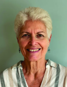 Smiling elderly woman with short white hair in a striped blouse.