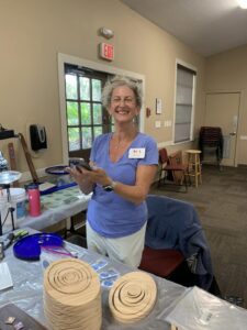 Smiling woman holding a black plate in a casual indoor setting.