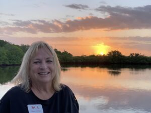Woman smiling by a serene lakeside during sunset.