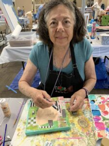 Woman painting a small canvas at an art workshop.