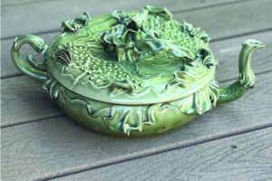Green ceramic trinket box with intricate floral and leaf designs.