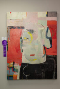 Abstract painting with layered colors and shapes, featuring a prominent face-like figure.