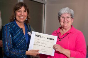 Two women smiling, one holding a certificate from YMCA.