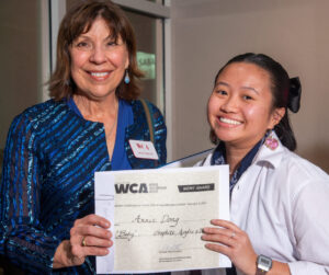 Two women smiling, one holding a certificate.