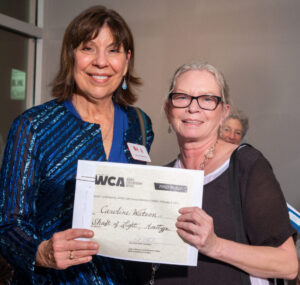 Two women smiling, holding a certificate together.