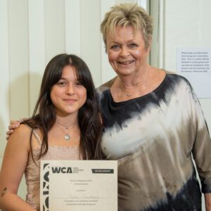 Two women smiling, one holding a certificate.