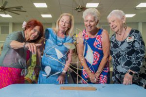 Four elderly women enjoying a game together indoors.