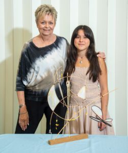 Two women posing together, one in a tie-dye top, the other in a light dress.