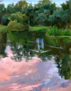 A serene pond reflecting trees and a pink sky.