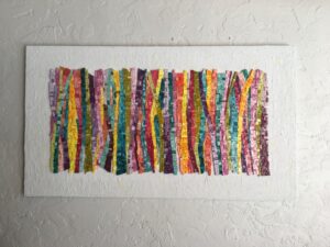 Colorful vertical stripes woven textile hanging on a white wall.