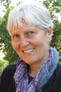 Smiling elderly woman with short white hair outdoors.