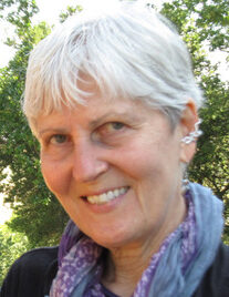 Smiling elderly woman with short white hair outdoors.