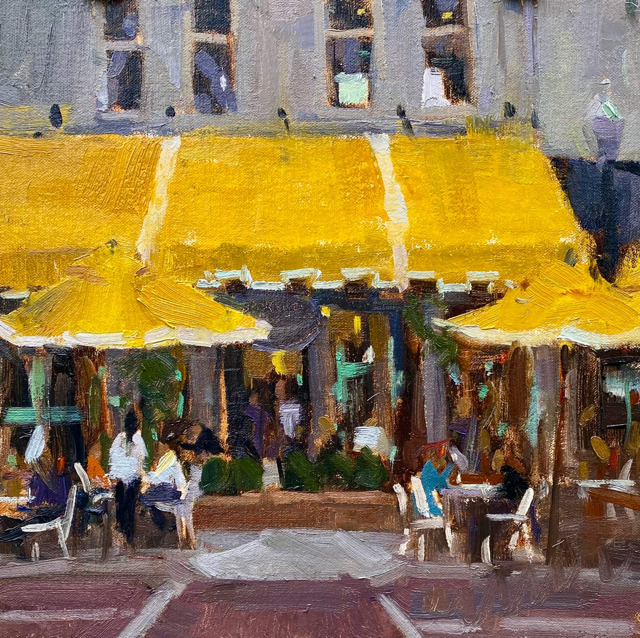 Outdoor café scene with yellow awnings and people dining.