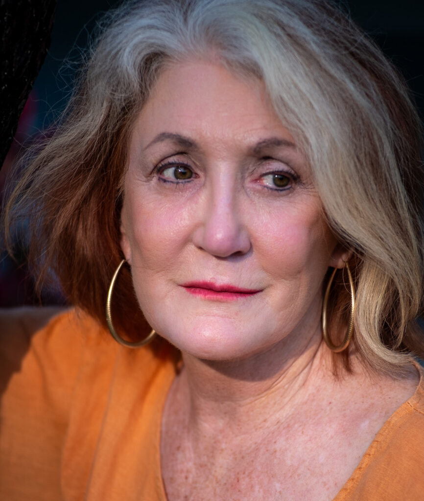 Portrait of an older woman with gray hair and hoop earrings.
