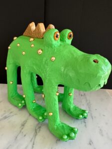 A green, handmade crocodile sculpture with decorative beads.