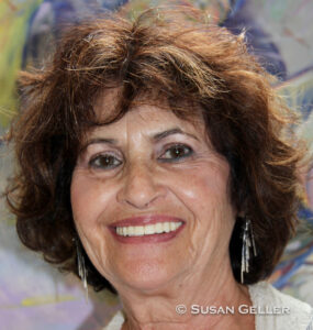 Smiling elderly woman with curly hair in a bright setting.