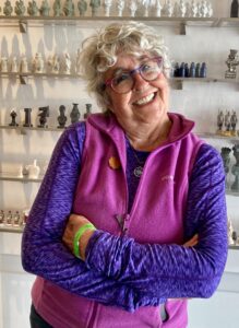 Elderly woman smiling warmly with colorful clothing and glasses.
