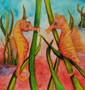 Two orange seahorses among green seaweed underwater.