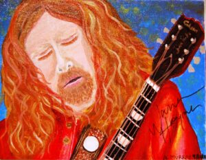 An emotional musician with long red hair playing guitar.