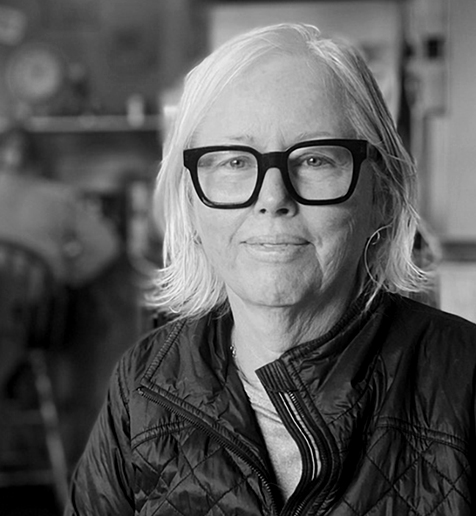 Black-and-white portrait of an elderly woman with glasses and long hair.