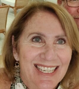 Smiling woman with light brown hair and dangling earrings.