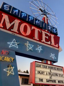 Vintage motel sign with neon stars and flags against the sky.