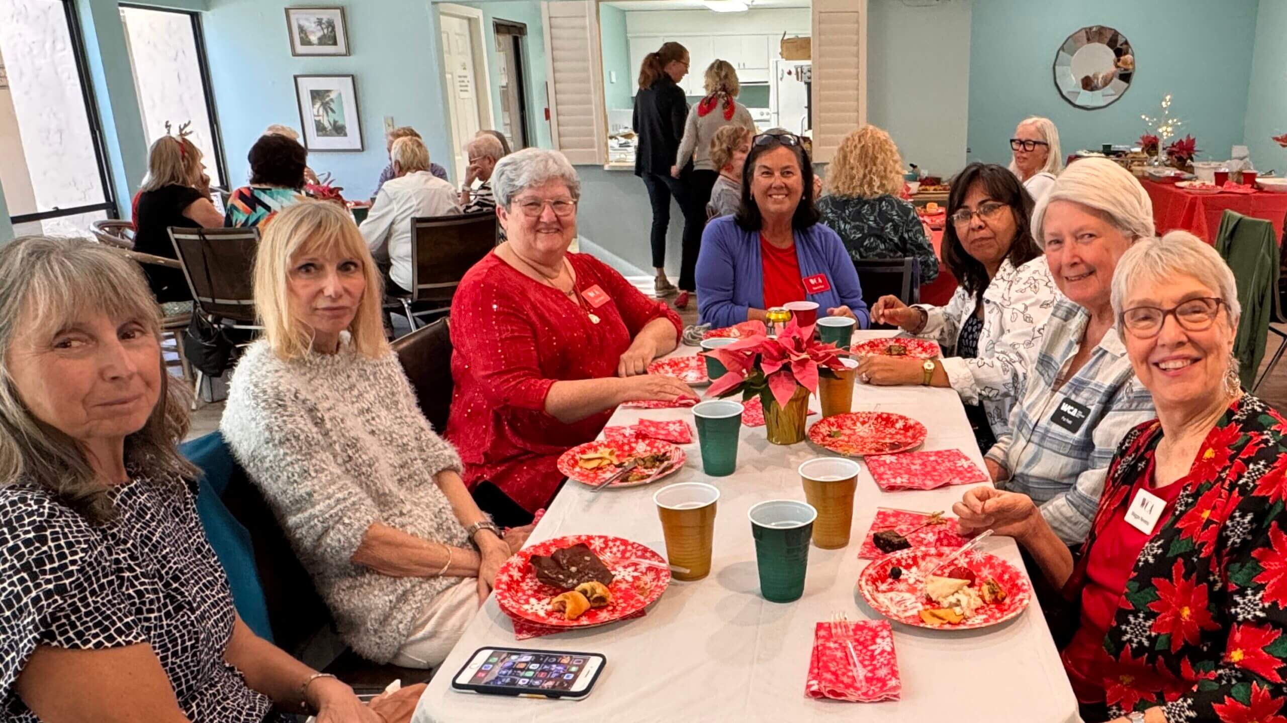 Four women enjoying a festive holiday gathering with food and decorations.