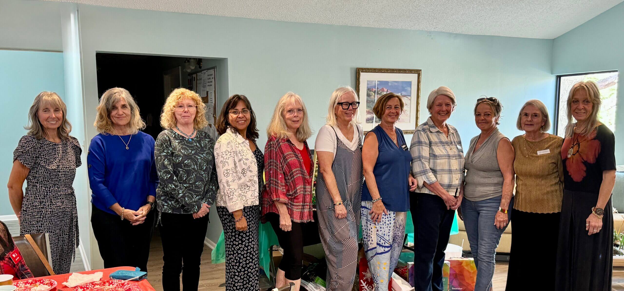 A group of six women posing indoors, dressed casually.
