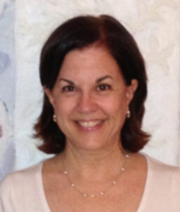 Smiling woman with short dark hair and a light top.