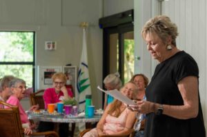 A woman reads to an attentive group in a cozy room.
