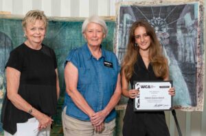 Three women, one holding a certificate, posing for a photo.