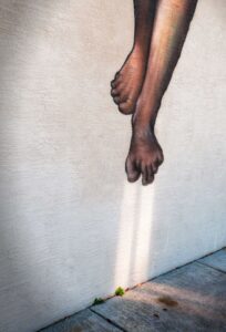 Street art of feet on textured wall.