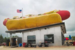Building with giant hot dog on roof.