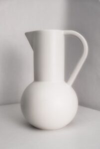 White ceramic pitcher on plain background.