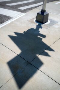 Shadow of street sign on sidewalk.