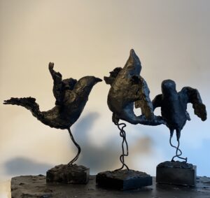 Three abstract bird sculptures on stands.